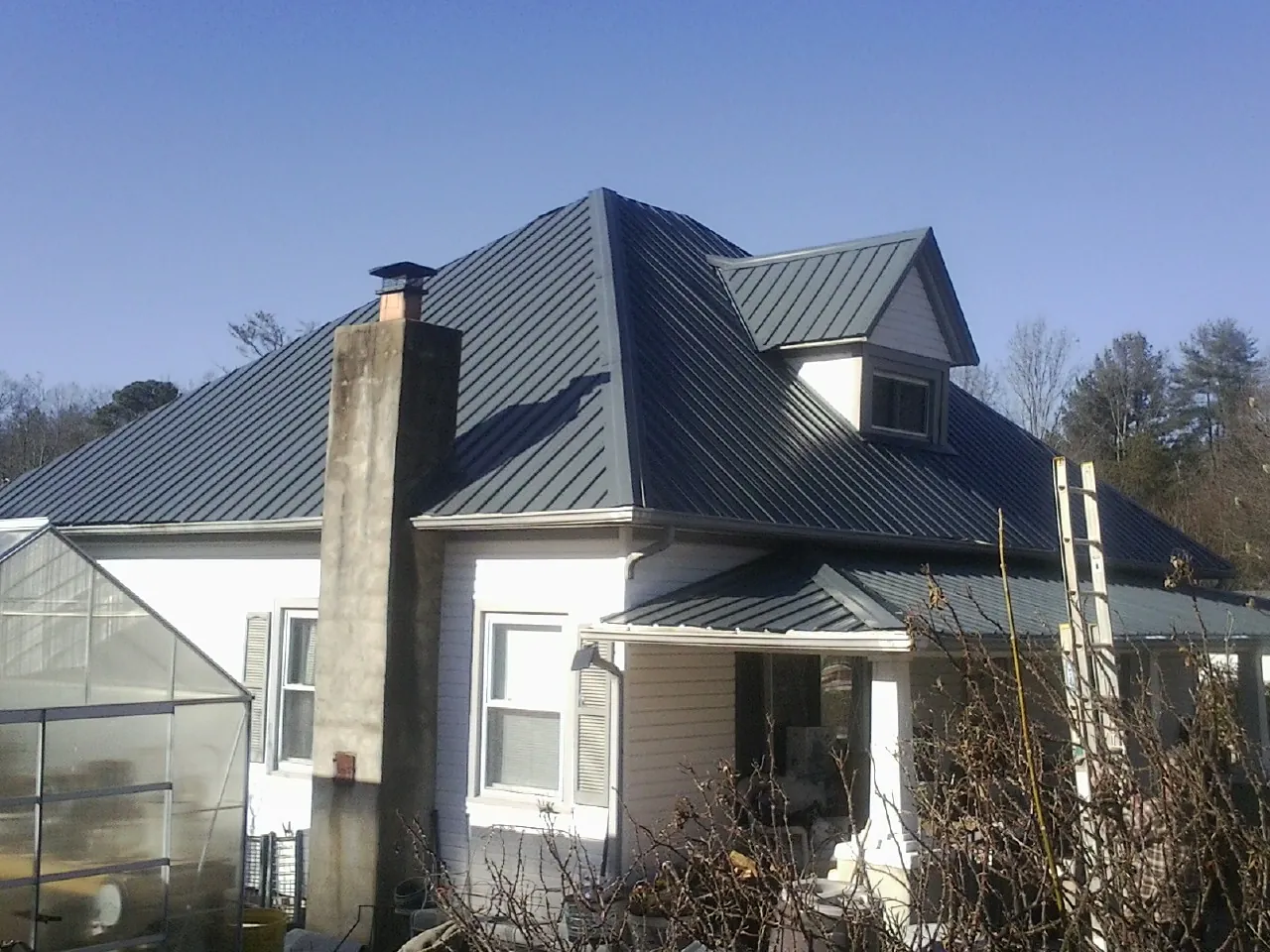 Dark blue standing seam metal roof on a white farmhouse with dormer — Slate & Tile Roof Repair by Roofing Brothers in Vallejo