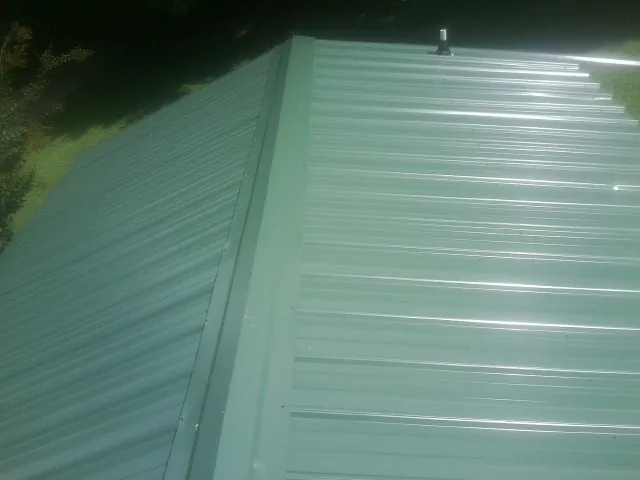 New green metal panels meeting at the ridge of a roof — Flat Roof Repair work by our crew in Vallejo