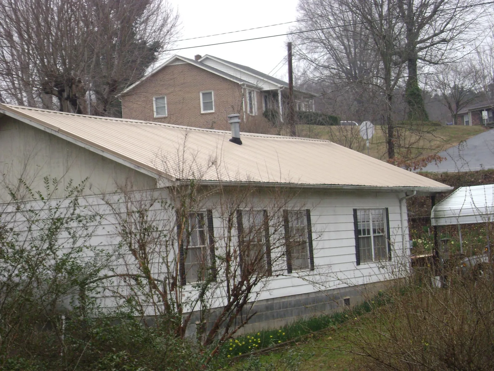 Tan metal roof on a white sided house set into a hillside — Commercial Roofing by Roofing Brothers in Vallejo
